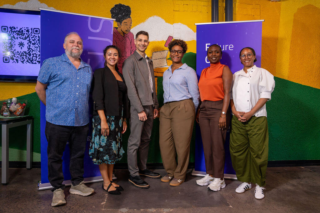 Conference participants posing in front of a colorful mural and FOCUS event banners.